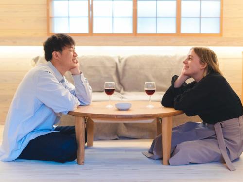 a man and woman sitting around a table with wine glasses at 竹田まちホテル in Taketa