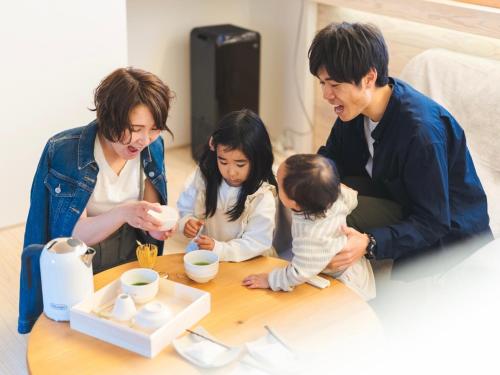 a man and a woman and two children sitting at a coffee table at 竹田まちホテル in Taketa