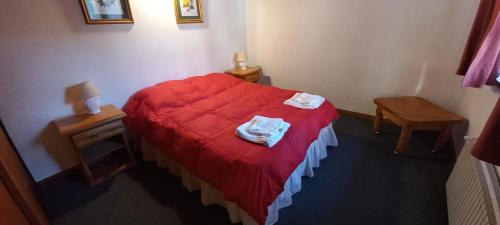 1 dormitorio con 1 cama roja y 2 toallas en Complejo Ciprés en San Martín de los Andes