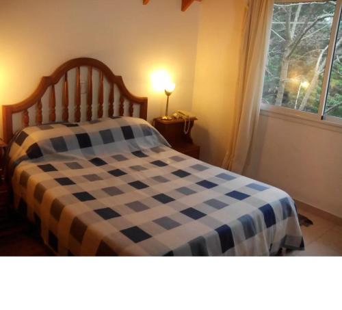 a bed with a blue and white checkered blanket at El lugar in Villa Gesell
