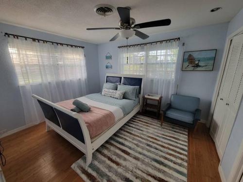 a bedroom with a bed and a fan and a chair at Beach & Surf Hacienda on Hutchinson Island in Fort Pierce