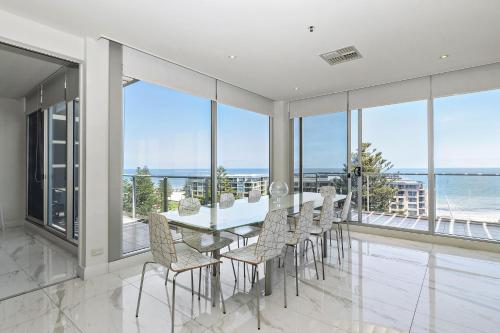 a dining room with a table and chairs and the ocean at Belle Escapes - Glenelg Skyline Penthouse in Glenelg
