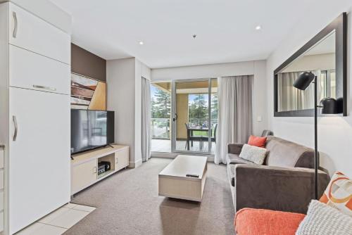 a living room with a couch and a tv at Belle Escapes - Glenelg Shores Apartment in Glenelg