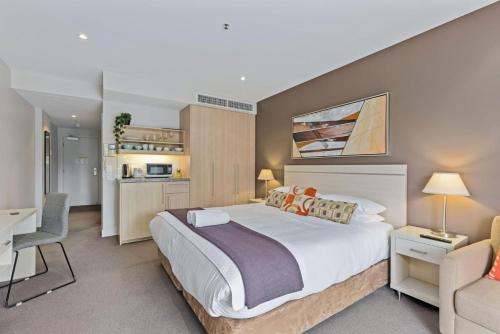a bedroom with a large white bed and a desk at Belle Escapes - Glenelg Shores Studio in Glenelg