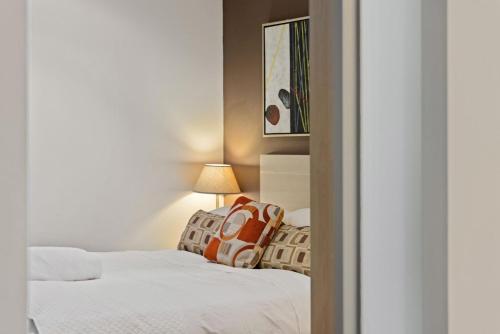 1 dormitorio con 2 camas con sábanas blancas y lámpara en Belle Escapes - Glenelg Shores Family Stay, en Glenelg