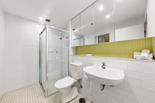 a white bathroom with a toilet and a sink at Belle Escapes - Lazy Days on Colley Terrace in Glenelg