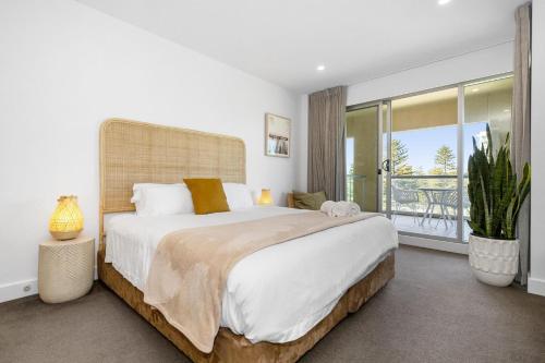 ein Schlafzimmer mit einem großen Bett und einem Balkon in der Unterkunft Belle Escapes - Park View Family Stay at the Pier in Glenelg