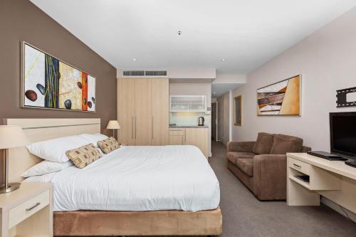 a bedroom with a large bed and a couch at Belle Escapes - Glenelg Seaside Studio in Glenelg