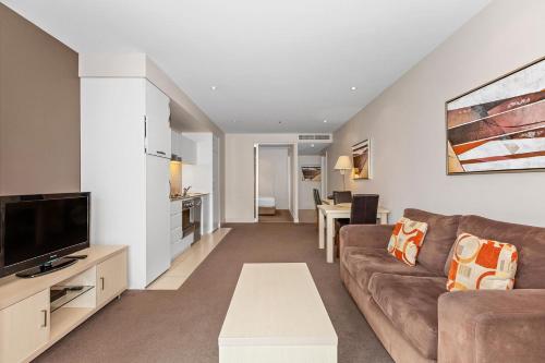 a living room with a couch and a tv at Belle Escapes - Glenelg Seaside Apartment in Glenelg