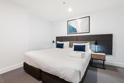 a bedroom with a large white bed with blue pillows at Belle Escapes - Sunset Views at the Bay in Glenelg