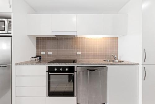 Una cocina blanca con estufa y fregadero. en Belle Escapes - Sunset Views at the Bay, en Glenelg