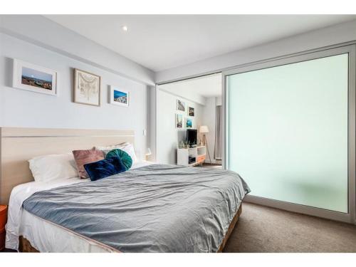 a bedroom with a bed and a large sliding glass door at Belle Escapes - Absolute Ocean Views in Glenelg