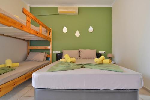 two beds in a room with green walls at Studios Λύδια in Paralía Skotínis