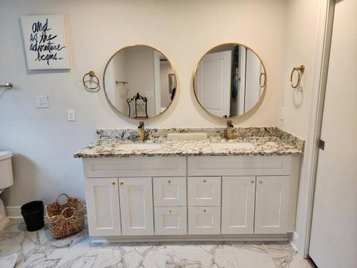 a bathroom with two sinks and two mirrors at Maison Franklin in New Orleans
