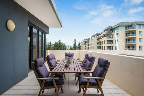 patio con mesa y sillas en el balcón en Belle Escapes - Glenelg Oceanview Apartment en Adelaida