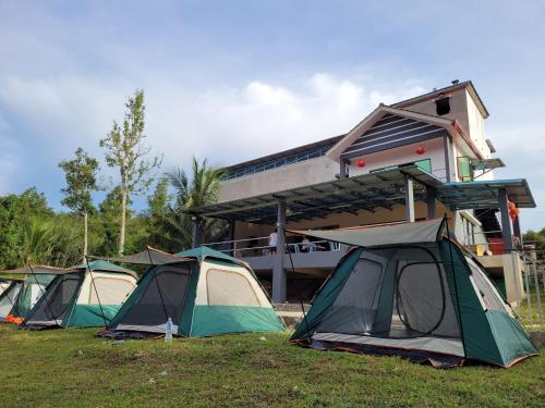 a group of tents sitting in the grass in front of a building at Lipis Riverfront Resort in Kuala Lipis