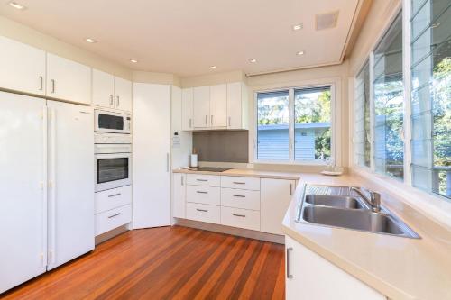 a kitchen with white cabinets and a sink at Iluka at Blueys Beach in Blueys Beach