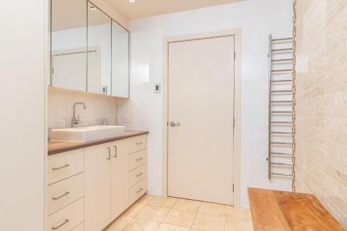 a white kitchen with a sink and a door at Iluka at Blueys Beach in Blueys Beach