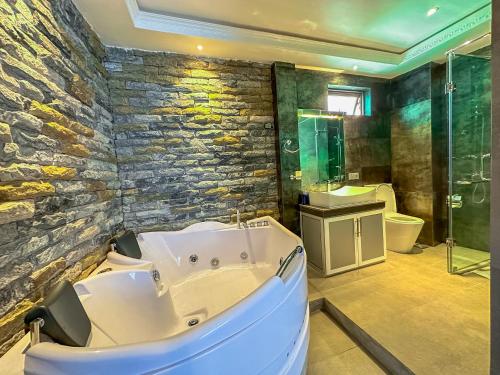 a bathroom with a tub and a stone wall at Baron Luxury Boutique in Nuwara Eliya