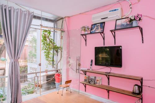 Habitación rosa con TV y ventana en Kim's Homestay Center of Ha Noi en Hanói