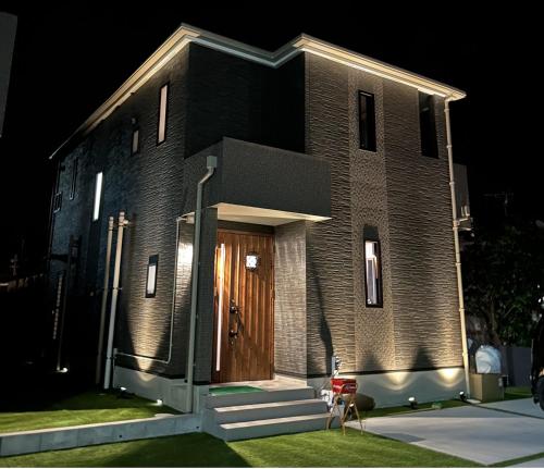 a brick building with a wooden door at night at The Ritz Okinawa Kise 2-Free parking for 2 cars, 3LDK, 2 bathrooms in Nago