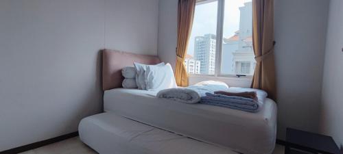 een kamer met een raam en een bed met handdoeken bij Convenient Apartments at West Jakarta in Jakarta