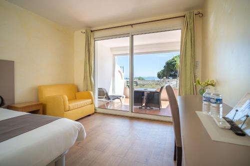 a hotel room with a bed and a view of the ocean at Hôtel Beau Soleil in Le Lavandou