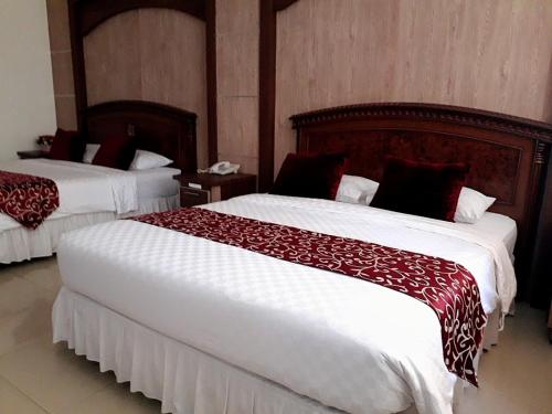 um quarto de hotel com duas camas com lençóis vermelhos e brancos em THE IGNISLO HOTEL SORONG em Sorong