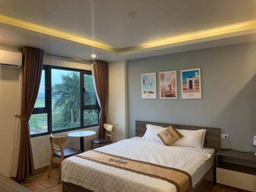 a bedroom with a bed and a table and a window at NEW SKY AIRPORT HOTEL NỘI BÀI in Noi Bai