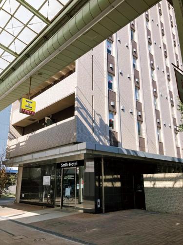 a large building with a sign in front of it at Smile Hotel Kokura in Kitakyushu