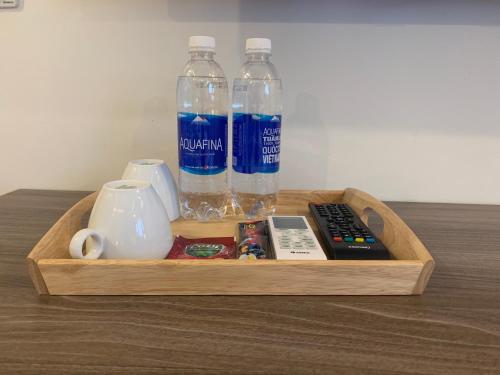 uma bandeja de madeira com garrafas de água e um controlo remoto em NEW SKY AIRPORT HOTEL NỘI BÀI em Noi Bai