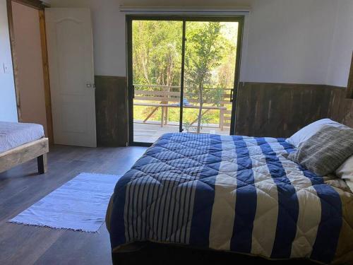 a bedroom with a bed and a large window at Casa en Futrono - Llifén-Ranco (tinaja adicional) in Futrono