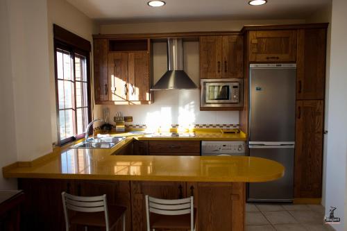 a kitchen with wooden cabinets and a yellow counter top at Alojamiento Nohal in La Iruela