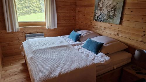 Un dormitorio con una cama con almohadas azules y una ventana en Gemütliches Ferienhaus mit Holzofen und Sauna, en Hohentauern