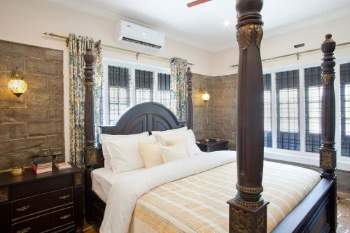 a bedroom with a large bed in a room with windows at StayVista at The Stone Villa with Basketball Court in Kozhikode