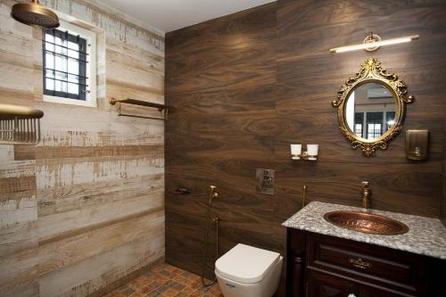 uma casa de banho com um WC e um espelho. em StayVista at The Stone Villa with Basketball Court em Calecute