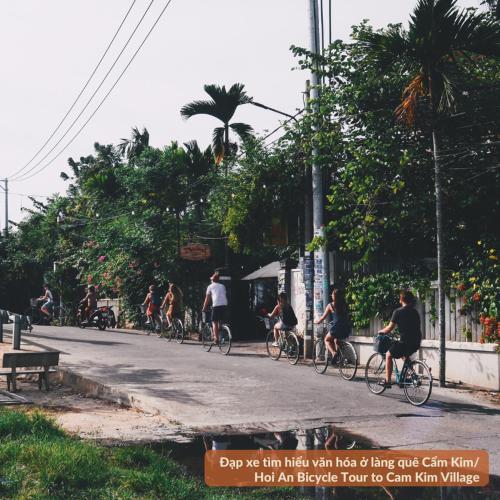 a group of people riding bikes down a street at HY Local Budget Hotel - 5 mins walk to Hoi An Ancient Town in Hoi An