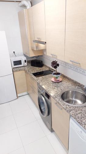 a kitchen with a sink and a washing machine at Apartamento en la playa con parking privado in Getxo