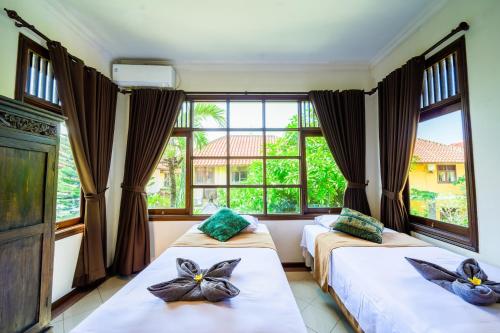 Villa SANKET - KUTA - 6 bedrooms - 6 bathrooms - Great Location في كوتا: سريرين في غرفة مع نافذة