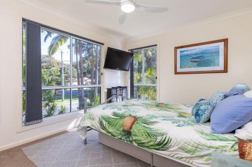 Schlafzimmer mit einem Bett, einem TV und Fenstern in der Unterkunft Pacific Palms in Elizabeth Beach