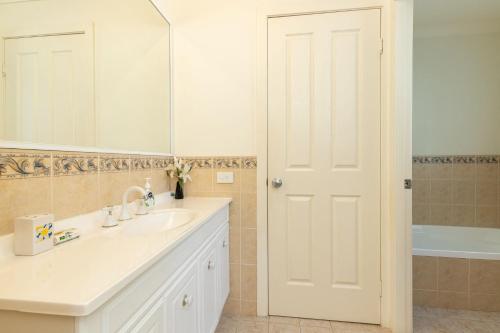 ein Badezimmer mit einem Waschbecken, einem Spiegel und einer Badewanne in der Unterkunft Pacific Palms in Elizabeth Beach