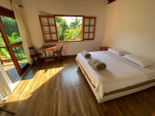 um quarto com uma cama grande e uma janela grande em Ycatu Beach House em São Sebastião