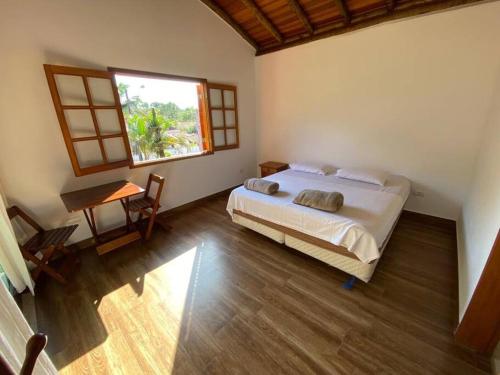 a bedroom with a bed and a window and a table at Ycatu Beach House in São Sebastião
