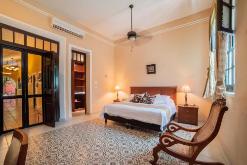 a bedroom with a bed and a chair at Espectacular casona con alberca y jardines in Mérida