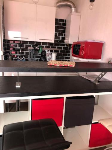 une cuisine avec un comptoir et un appareil rouge dans l'établissement location studio 4 pers piscine, au Cap d'Agde