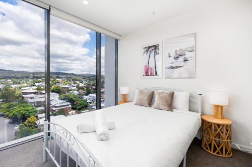 a bedroom with a white bed and a large window at Brandnew Spacious and Stunning 1bed Apartment in Brisbane