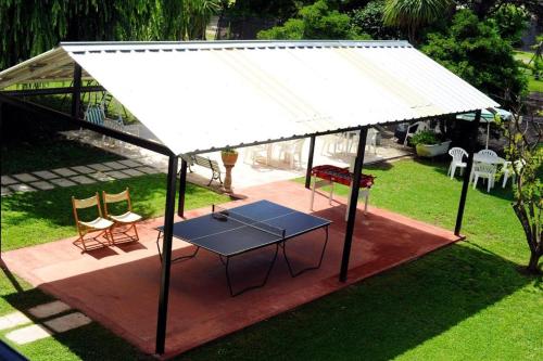 a pavilion with a table and chairs in a yard at Las Camelias Apart in Chascomús