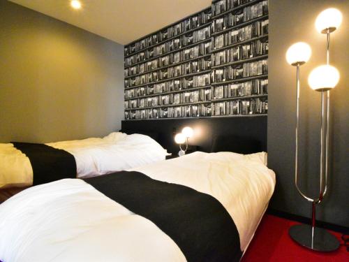 two beds in a room with a wall with books at The Garden Place Hiroshima - Vacation STAY 89276v in Hiroshima