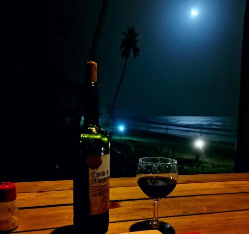 a bottle of wine and a glass on a table at Afro Beach eco Resort Butre in Butre