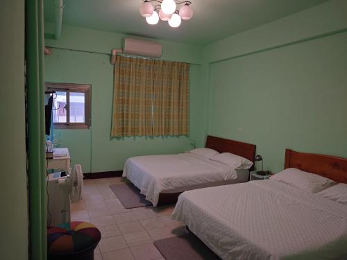 a green room with two beds and a window at 里山旅棧民宿 Li Shan Homestay in Fuli